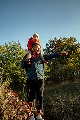 Image showing Happy father and little cute daughter walking down the forest path in autumn sunny day