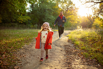 Image showing Happy father and little cute daughter walking down the forest path in autumn sunny day