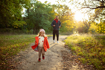 Image showing Happy father and little cute daughter walking down the forest path in autumn sunny day