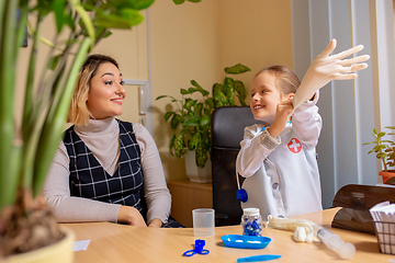 Image showing Paediatrician doctor examining a child in comfortabe medical office. Little girl playing pretends like doctor for woman