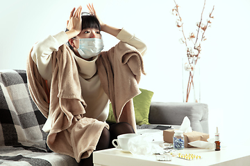 Image showing Woman wrapped in a plaid and wearing face mask trying to protect herself from somebody\'s sick near by