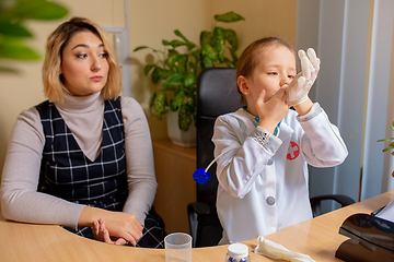 Image showing Paediatrician doctor examining a child in comfortabe medical office. Little girl playing pretends like doctor for woman