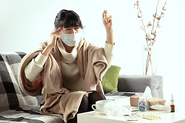 Image showing Woman wrapped in a plaid and wearing face mask trying to protect herself from somebody\'s sick near by