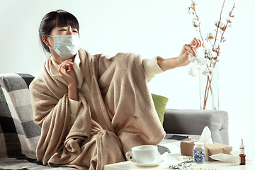 Image showing Woman wrapped in a plaid and wearing face mask trying to protect herself from somebody\'s sick near by