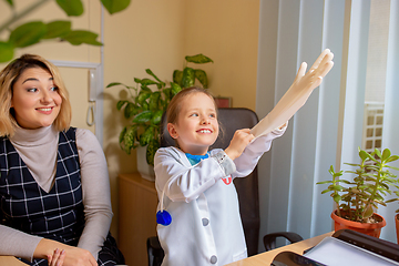 Image showing Paediatrician doctor examining a child in comfortabe medical office. Little girl playing pretends like doctor for woman