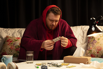 Image showing Man wrapped in a plaid looks sick, ill, sneezing and coughing sitting at home indoors