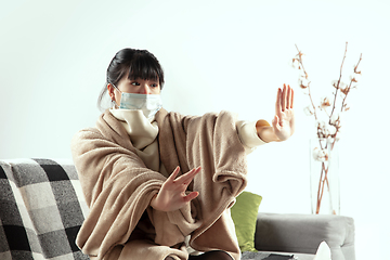 Image showing Woman wrapped in a plaid and wearing face mask trying to protect herself from somebody\'s sick near by