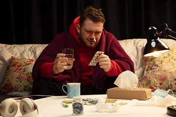 Image showing Man wrapped in a plaid looks sick, ill, sneezing and coughing sitting at home indoors