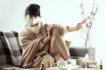 Image showing Woman wrapped in a plaid and wearing face mask trying to protect herself from somebody\'s sick near by