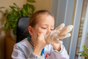 Image showing Paediatrician doctor examining a child in comfortabe medical office. Little girl playing pretends like doctor for woman