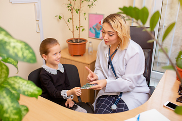 Image showing Paediatrician doctor examining a child in comfortabe medical office