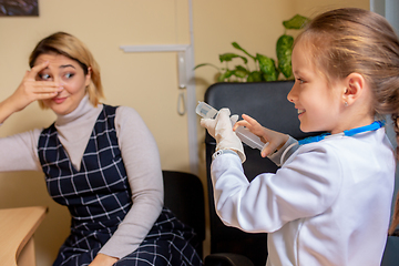 Image showing Paediatrician doctor examining a child in comfortabe medical office. Little girl playing pretends like doctor for woman