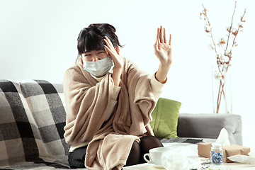 Image showing Woman wrapped in a plaid and wearing face mask trying to protect herself from somebody\'s sick near by