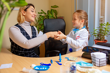 Image showing Paediatrician doctor examining a child in comfortabe medical office. Little girl playing pretends like doctor for woman