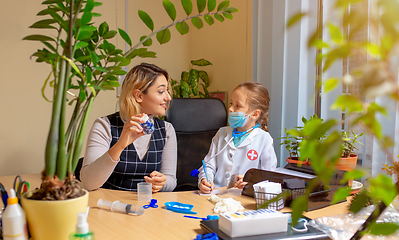 Image showing Paediatrician doctor examining a child in comfortabe medical office. Little girl playing pretends like doctor for woman