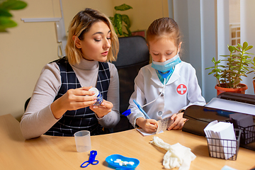 Image showing Paediatrician doctor examining a child in comfortabe medical office. Little girl playing pretends like doctor for woman