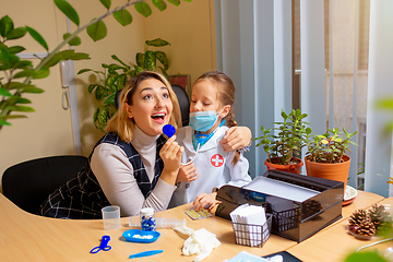 Image showing Paediatrician doctor examining a child in comfortabe medical office. Little girl playing pretends like doctor for woman