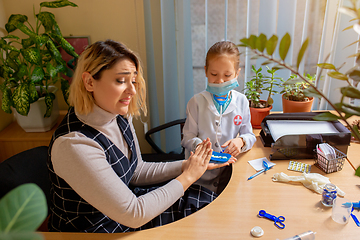 Image showing Paediatrician doctor examining a child in comfortabe medical office. Little girl playing pretends like doctor for woman