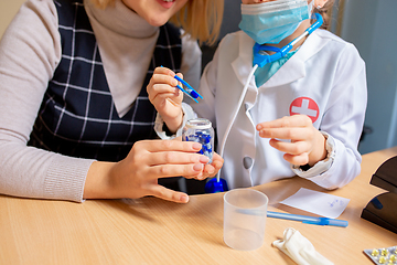 Image showing Paediatrician doctor examining a child in comfortabe medical office. Little girl playing pretends like doctor for woman