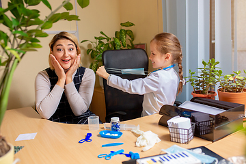 Image showing Paediatrician doctor examining a child in comfortabe medical office. Little girl playing pretends like doctor for woman