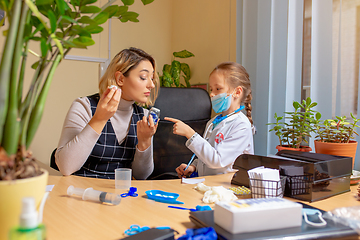 Image showing Paediatrician doctor examining a child in comfortabe medical office. Little girl playing pretends like doctor for woman