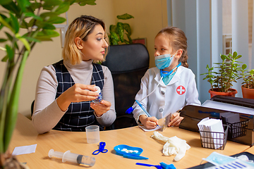 Image showing Paediatrician doctor examining a child in comfortabe medical office. Little girl playing pretends like doctor for woman