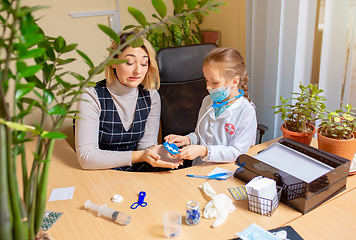 Image showing Paediatrician doctor examining a child in comfortabe medical office. Little girl playing pretends like doctor for woman