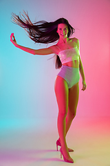 Image showing Beautiful seductive girl in fashionable swimsuit on bright gradient pink-blue background in neon light