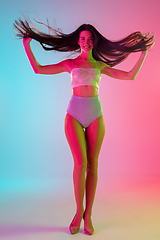 Image showing Beautiful seductive girl in fashionable swimsuit on bright gradient pink-blue background in neon light