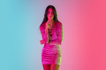 Image showing Beautiful seductive girl in fashionable dress, outfit on bright gradient pink-blue background in neon light