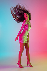 Image showing Beautiful seductive girl in fashionable dress, outfit on bright gradient pink-blue background in neon light