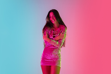 Image showing Beautiful seductive girl in fashionable dress, outfit on bright gradient pink-blue background in neon light