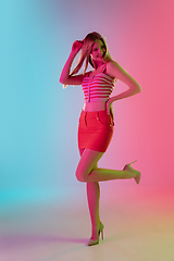 Image showing Beautiful girl in fashionable, romantic outfit on bright gradient pink-blue background in neon light