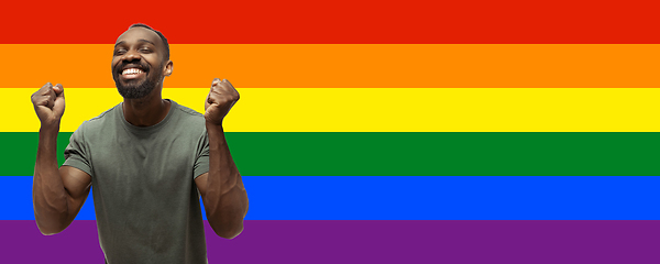 Image showing Young astonished african-american man on multicolored background forming a pride flag