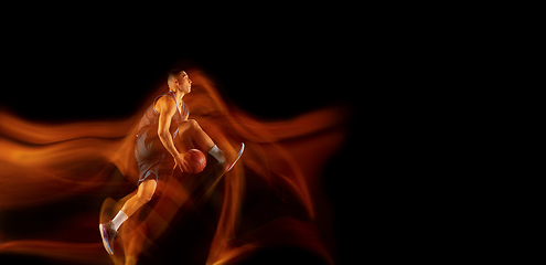 Image showing Young east asian basketball player in action and jump in mixed light over dark studio background. Concept of sport, movement, energy and dynamic, healthy lifestyle.