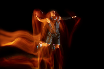 Image showing Young east asian basketball player in action and jump in mixed light over dark studio background. Concept of sport, movement, energy and dynamic, healthy lifestyle.