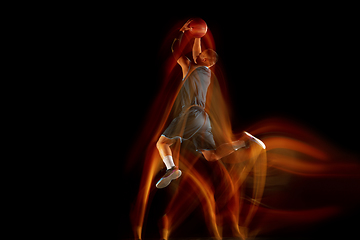 Image showing Young east asian basketball player in action and jump in mixed light over dark studio background. Concept of sport, movement, energy and dynamic, healthy lifestyle.