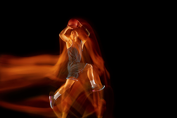 Image showing Young east asian basketball player in action and jump in mixed light over dark studio background. Concept of sport, movement, energy and dynamic, healthy lifestyle.