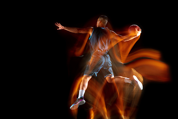 Image showing Young east asian basketball player in action and jump in mixed light over dark studio background. Concept of sport, movement, energy and dynamic, healthy lifestyle.