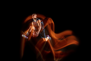 Image showing Young east asian basketball player in action and jump in mixed light over dark studio background. Concept of sport, movement, energy and dynamic, healthy lifestyle.