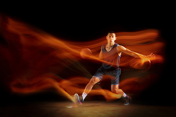 Image showing Young east asian basketball player in action and jump in mixed light over dark studio background. Concept of sport, movement, energy and dynamic, healthy lifestyle.