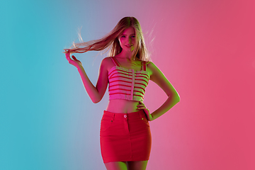 Image showing Beautiful girl in fashionable, romantic outfit on bright gradient pink-blue background in neon light