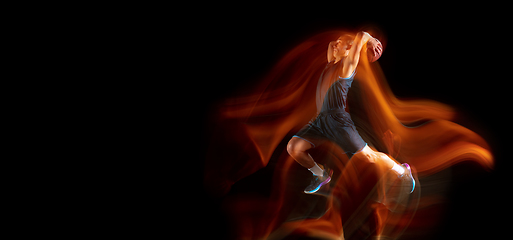 Image showing Young east asian basketball player in action and jump in mixed light over dark studio background. Concept of sport, movement, energy and dynamic, healthy lifestyle.