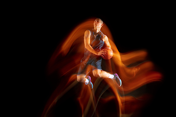 Image showing Young east asian basketball player in action and jump in mixed light over dark studio background. Concept of sport, movement, energy and dynamic, healthy lifestyle.