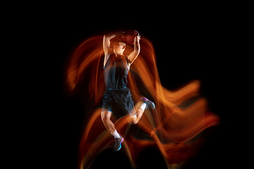 Image showing Young east asian basketball player in action and jump in mixed light over dark studio background. Concept of sport, movement, energy and dynamic, healthy lifestyle.