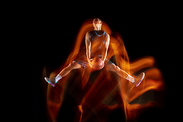 Image showing Young east asian basketball player in action and jump in mixed light over dark studio background. Concept of sport, movement, energy and dynamic, healthy lifestyle.