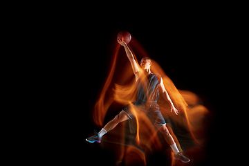 Image showing Young east asian basketball player in action and jump in mixed light over dark studio background. Concept of sport, movement, energy and dynamic, healthy lifestyle.