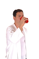 Image showing Tall man standing in bathrobe drinking coffee 