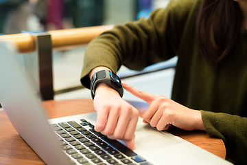 Image showing Woman connecting smart watch on laptop computer