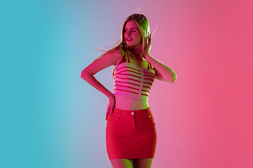 Image showing Beautiful girl in fashionable, romantic outfit on bright gradient pink-blue background in neon light